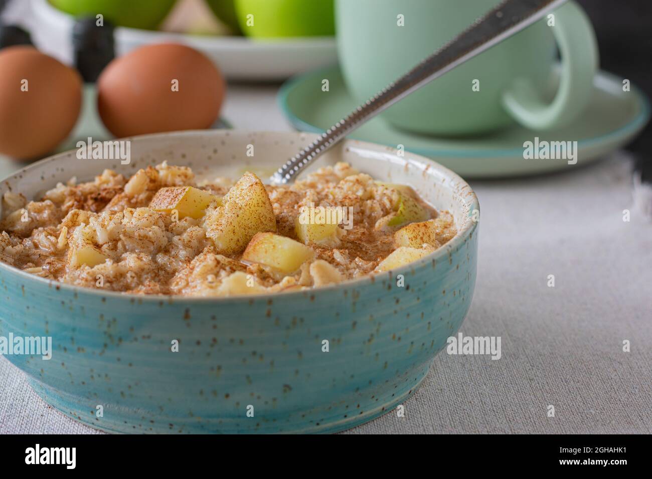 Porridge con mele cotte e cannella in una ciotola sul tavolo da cucina Foto Stock