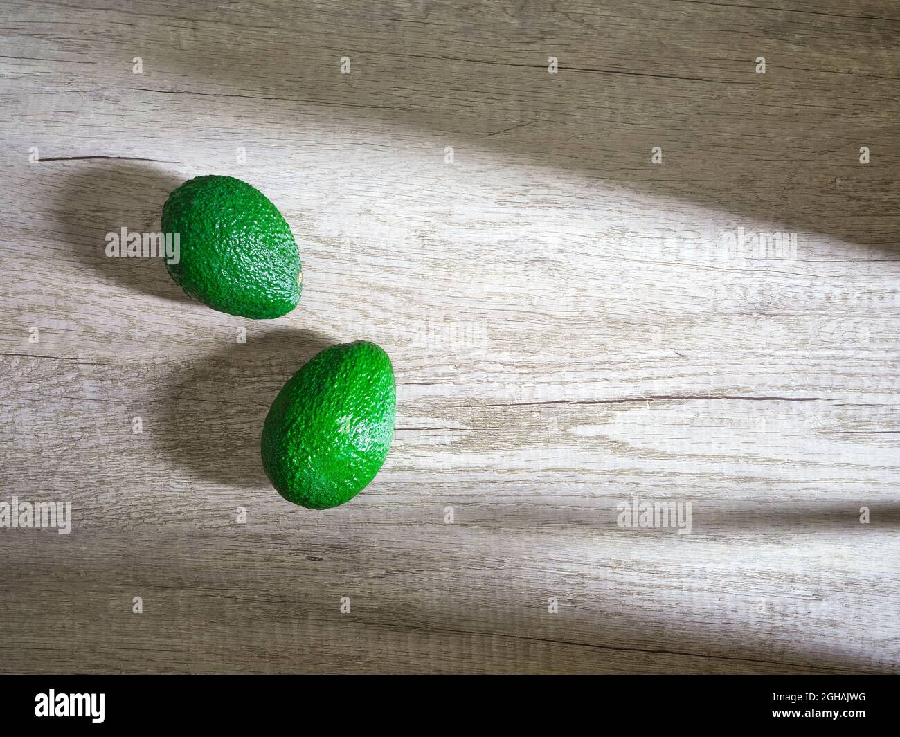due avocado verdi su superficie di legno Foto Stock