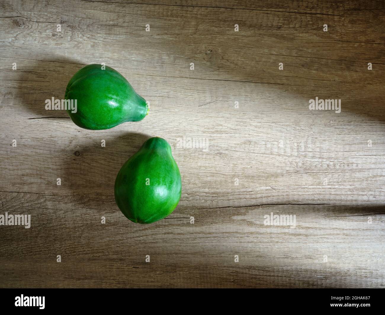 due papaie verdi con sfondo in legno Foto Stock
