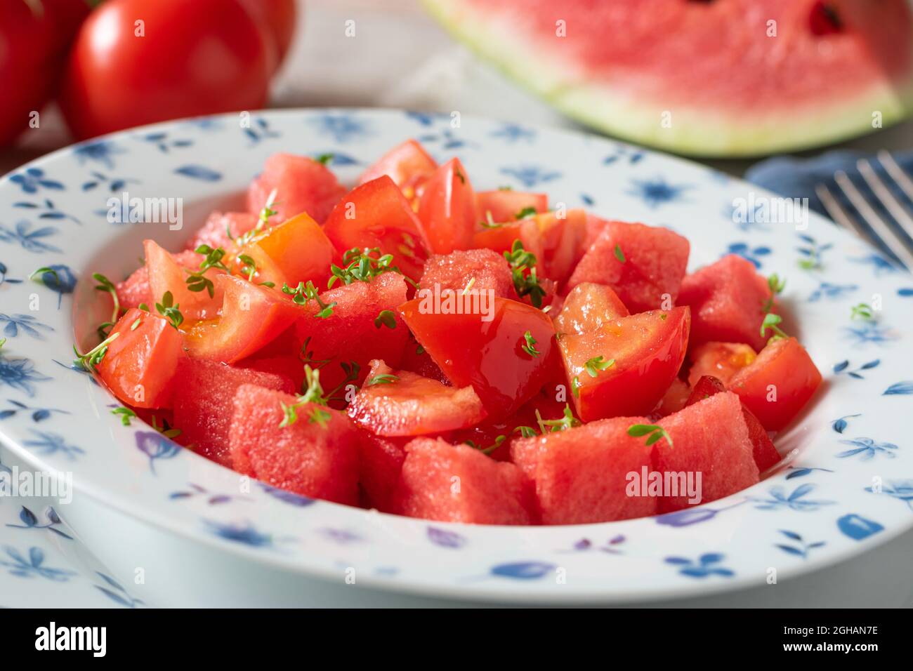 Insalata succosa con pomodori e cocomeri su un piatto con cress marinato con olio d'oliva. Delizioso spuntino estivo e soft Health food Foto Stock