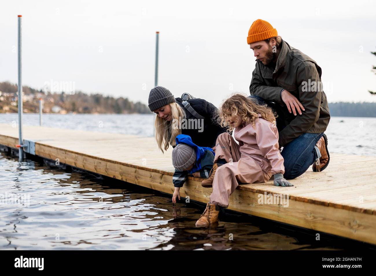 Uomo e donna con figlio e figlia sul molo al lago Foto Stock
