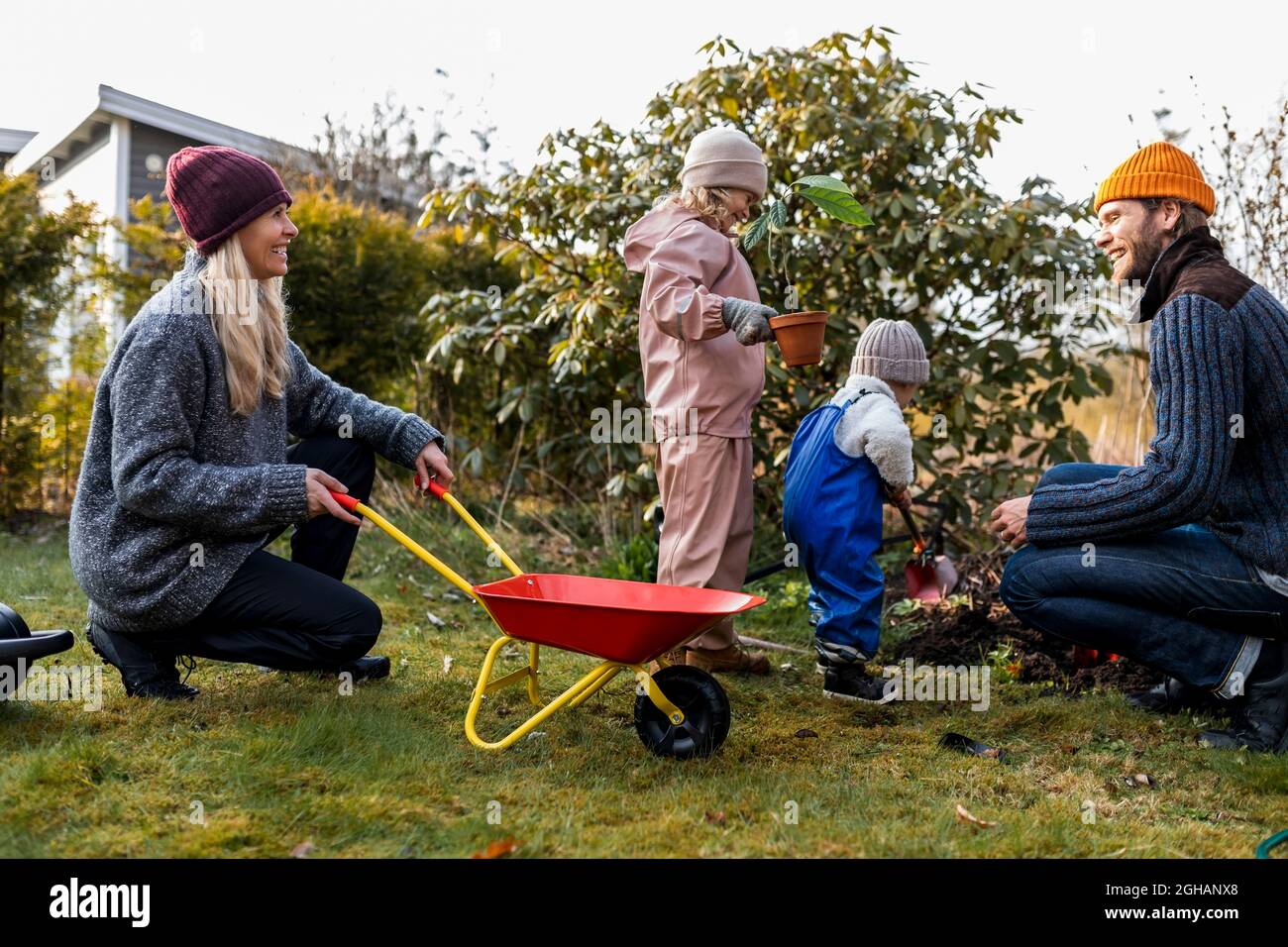 Famiglia felice facendo il giardinaggio insieme al cortile posteriore Foto Stock