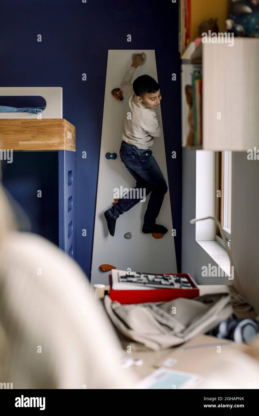 Ragazzo pre-adolescente parete di arrampicata in camera da letto Foto Stock