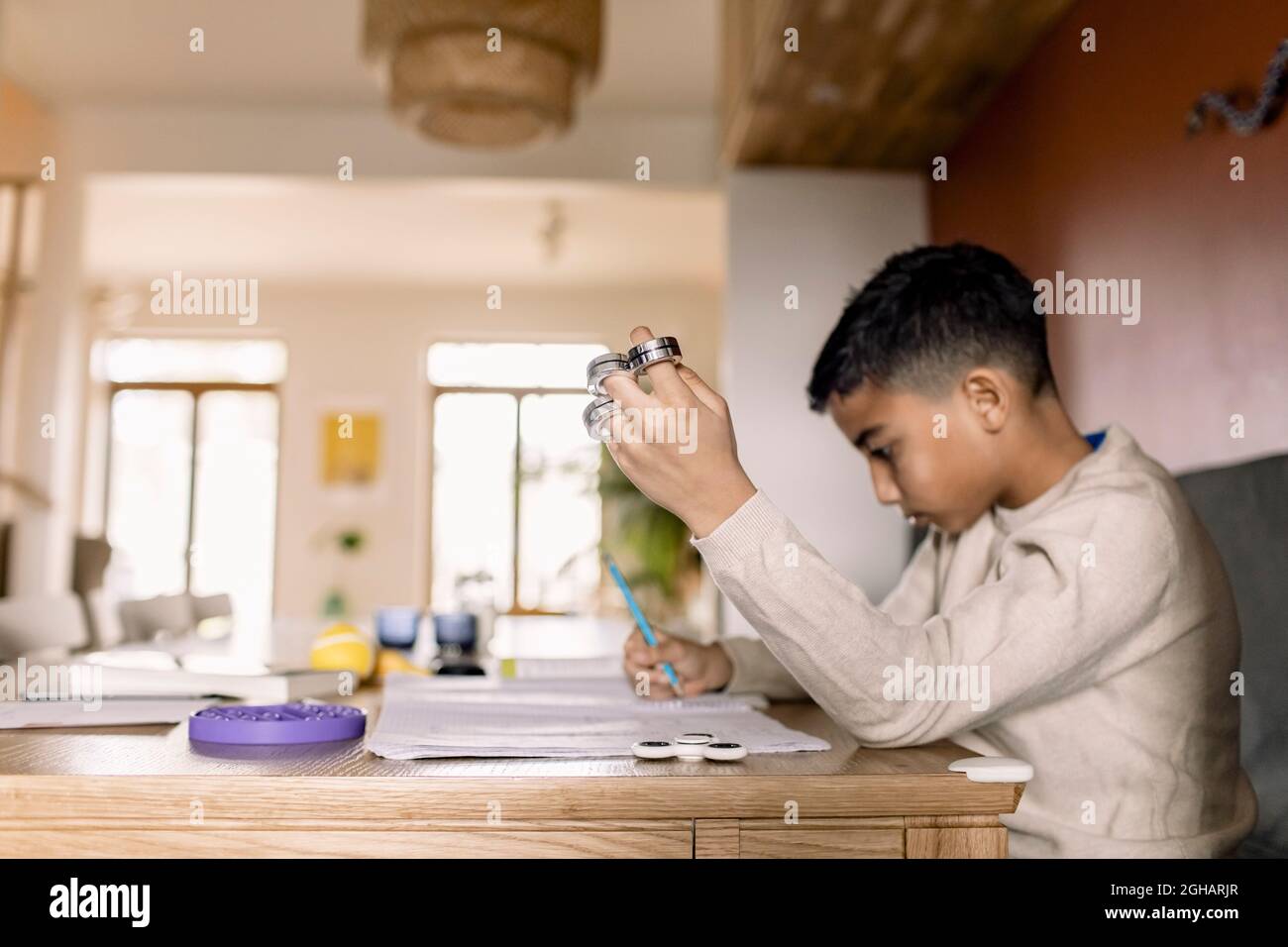 Ragazzo autistico iscritto nel libro mentre si siede a casa Foto Stock