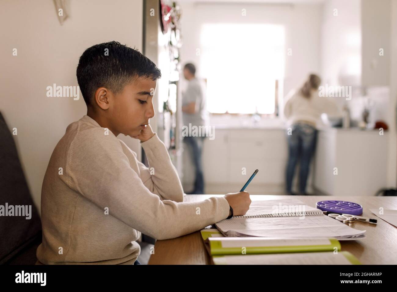 Ragazzo autistico iscritto nel libro sopra il tavolo a casa Foto Stock