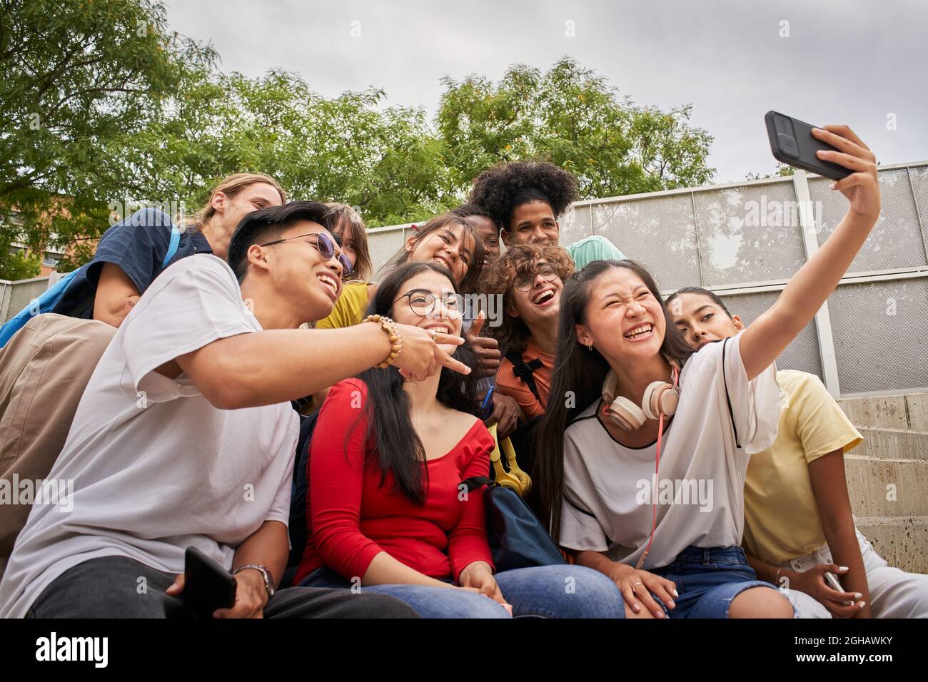 Gruppo di studenti multietnici che prendono selfie con il cellulare. Adolescenti che usano uno smartphone e si divertono insieme. Foto Stock