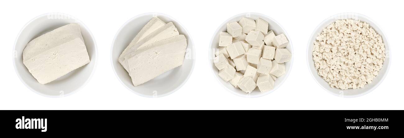 Tofu bianco lavorato, in ciotole bianche. Blocco singolo, tre fette, cubetti e tofu sbriciolato. Cagliata di fagiolo, fatta di latte di soia coagulato. Foto Stock
