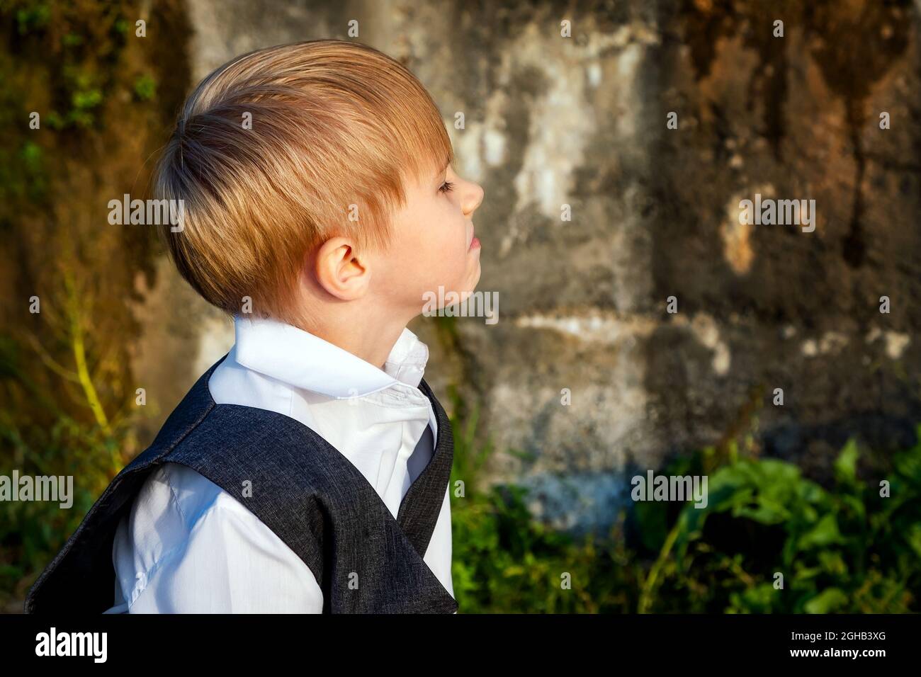 Ritratto di un triste Kid sul muro di cemento all'aperto Foto Stock