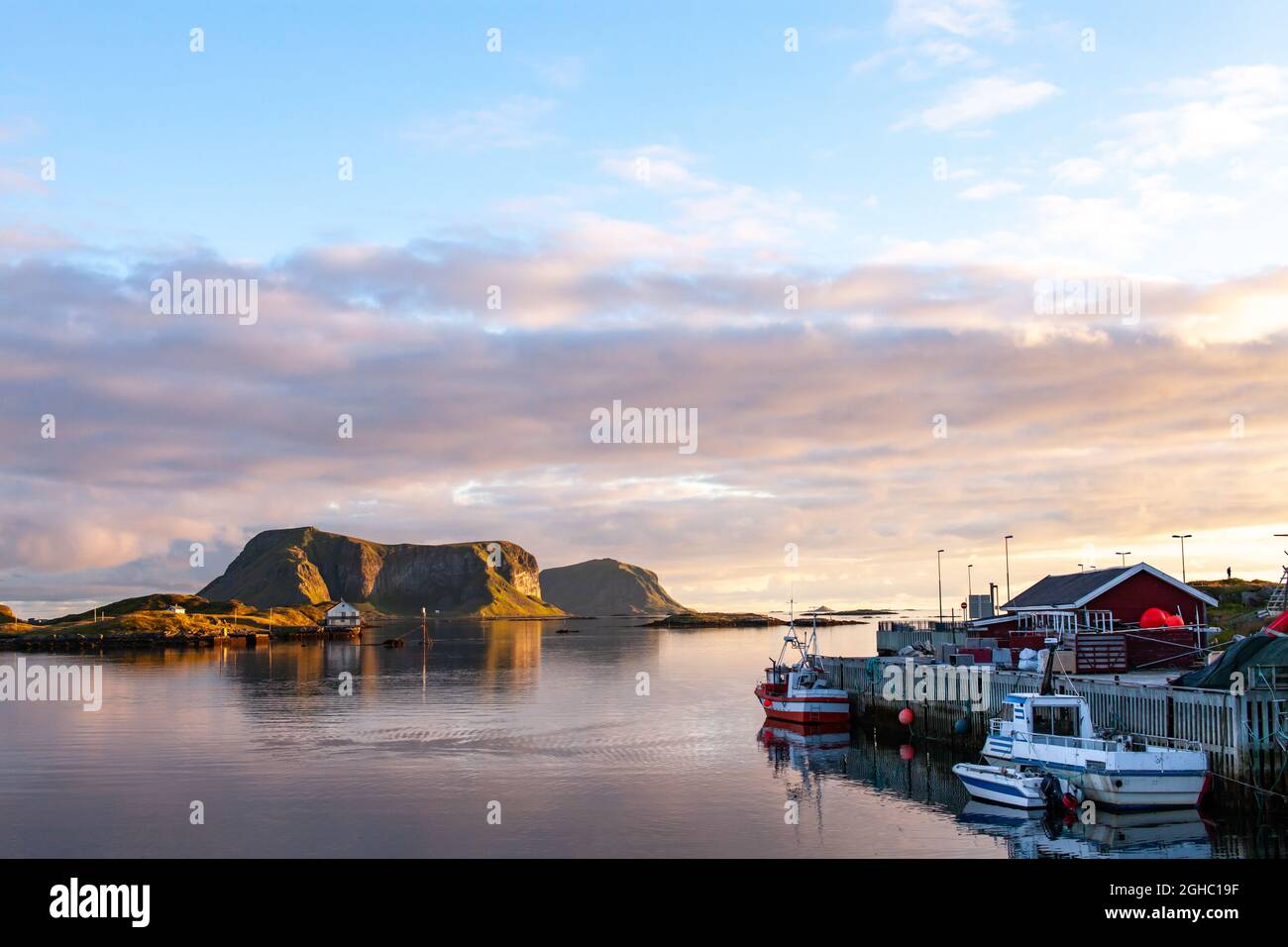 Bella vista delle barche da pesca con Vedøya sullo sfondo. Røst a Lofoten Norvegia. Foto Stock