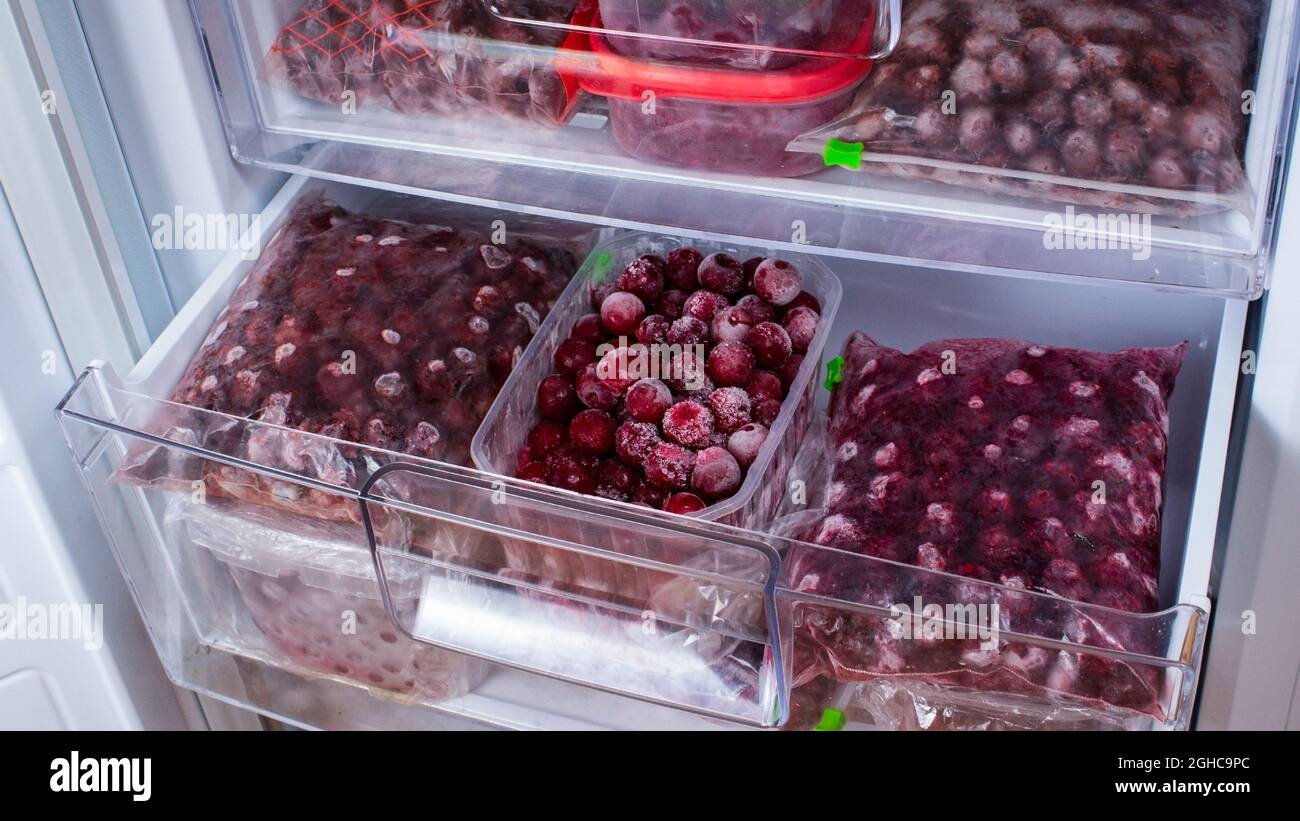 Le ciliegie congelate nel congelatore sono confezionate in scatole di  plastica e sacchetti di plastica. Aprire il congelatore con ciliegie rosse  congelate. Deposito di cibo. Cibo congelato Foto stock - Alamy