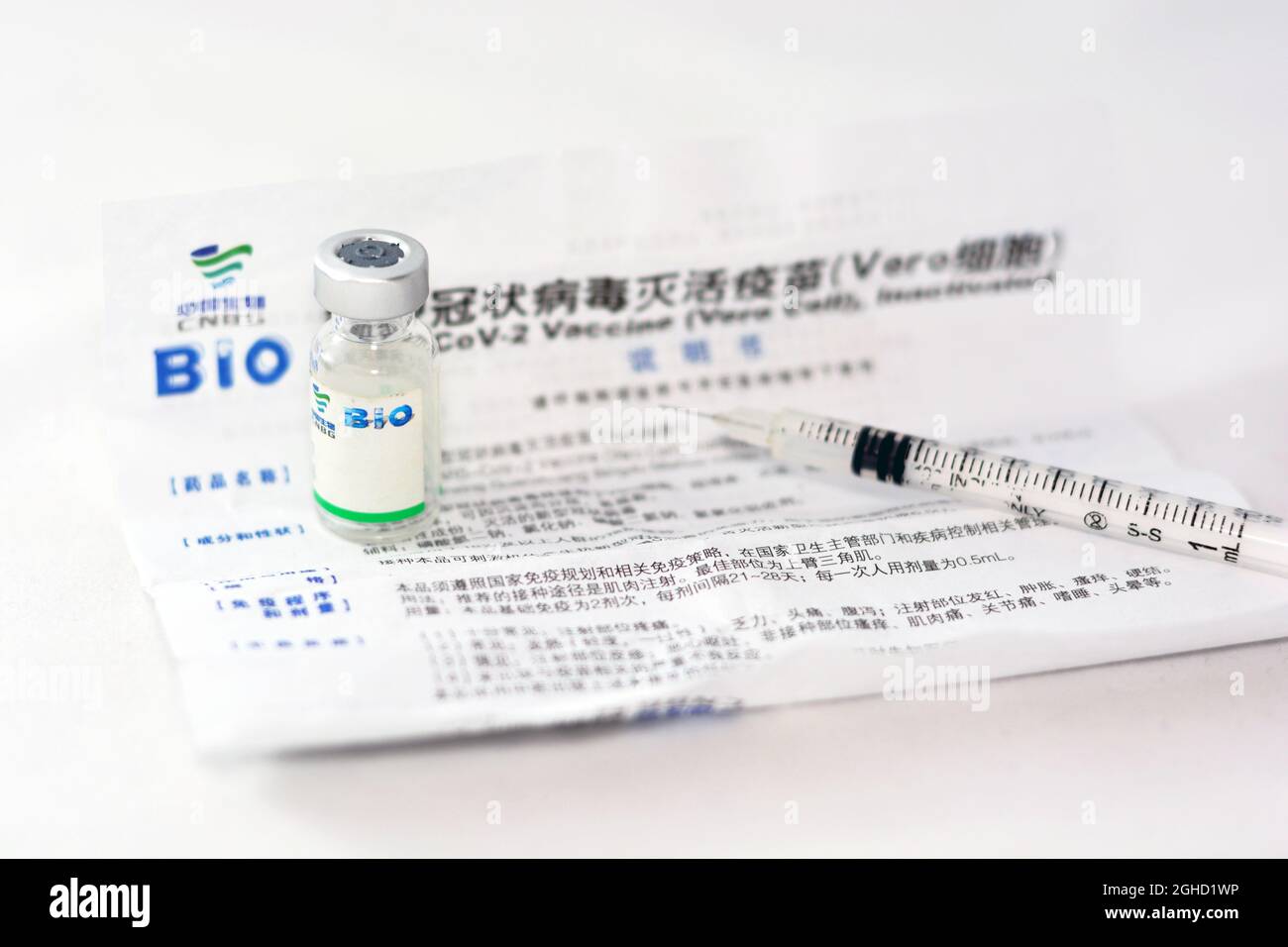 La dose del flacone di vaccino cinese Sinopharm COVID-19, il vaccino Sars-Cov-2 inattivato vero cellula con il foglio del vaccino e una siringa isolata su un bianco Foto Stock