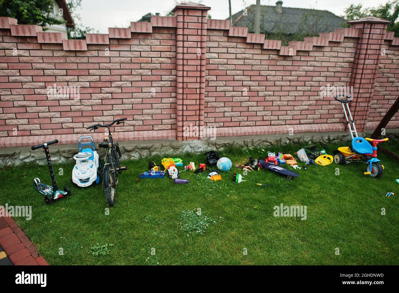 Diversi giocattoli e biciclette a casa in erba. Foto Stock