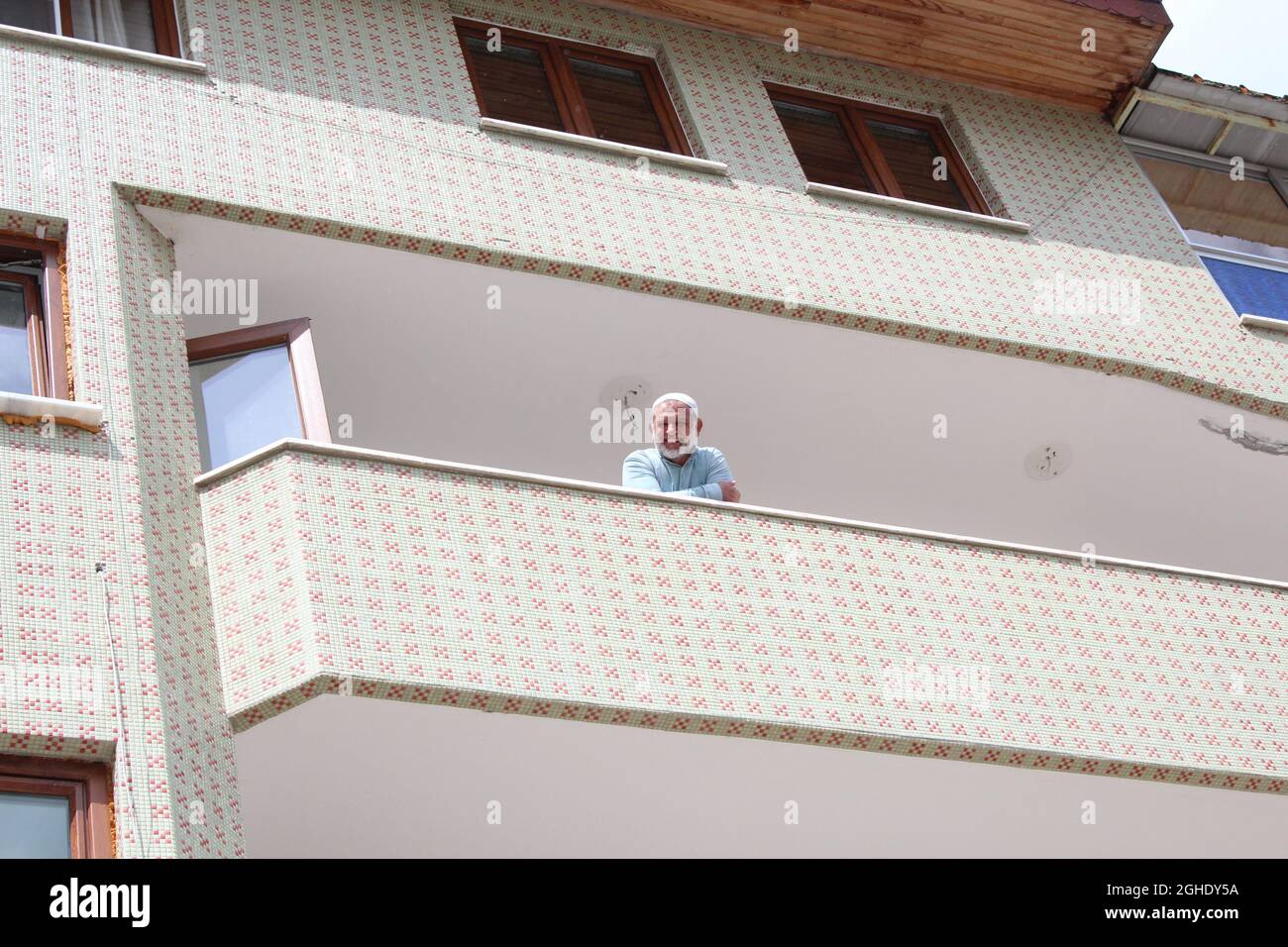 Uomo islamico anziano sorridendo dal balcone alla macchina fotografica e diffondendo la felicità. Foto Stock