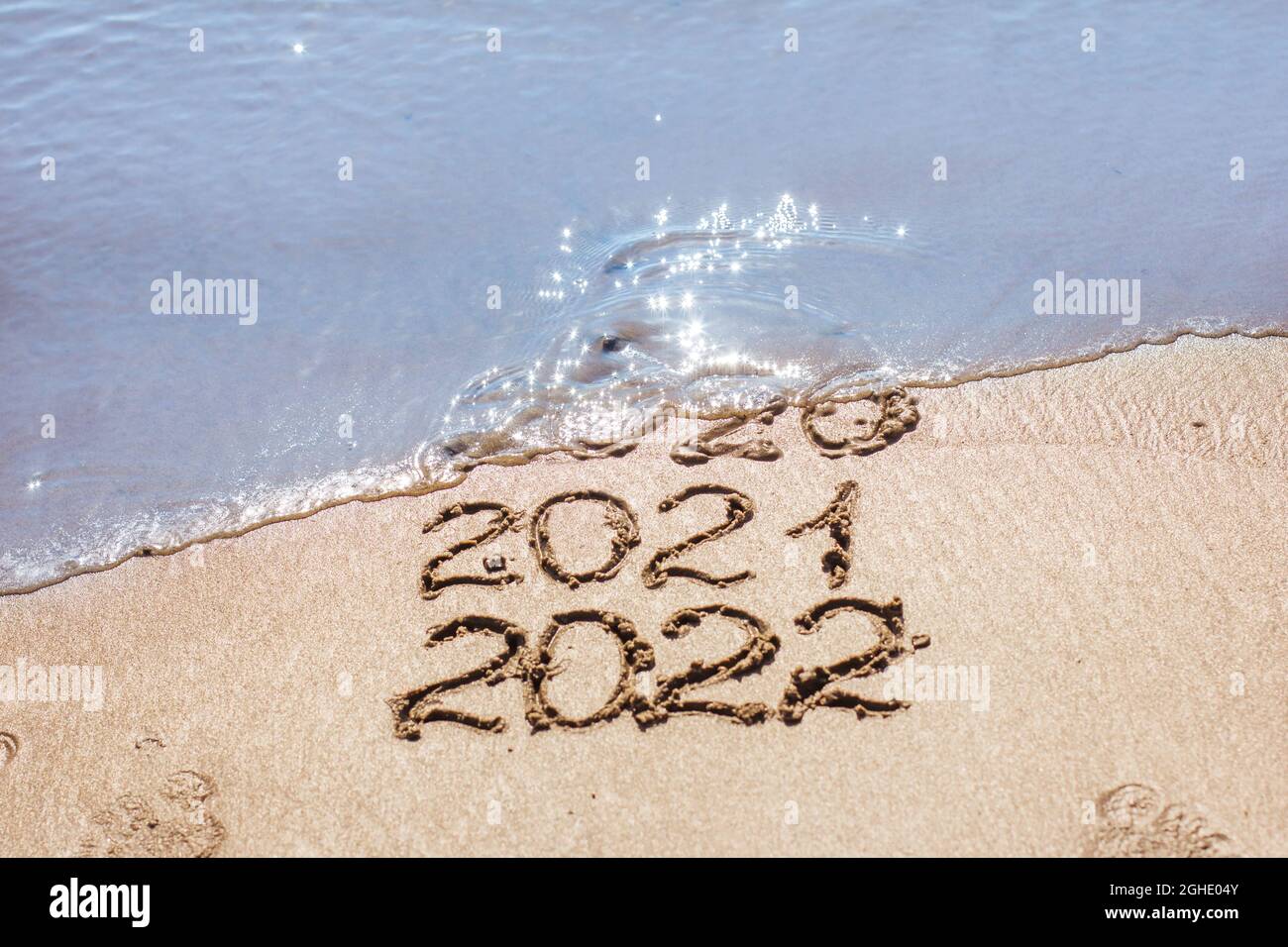I numeri 2021, 2022 sono disegnati sulla sabbia e lavati via dall'onda, il simbolo del nuovo anno, il cambiamento dell'anno Foto Stock