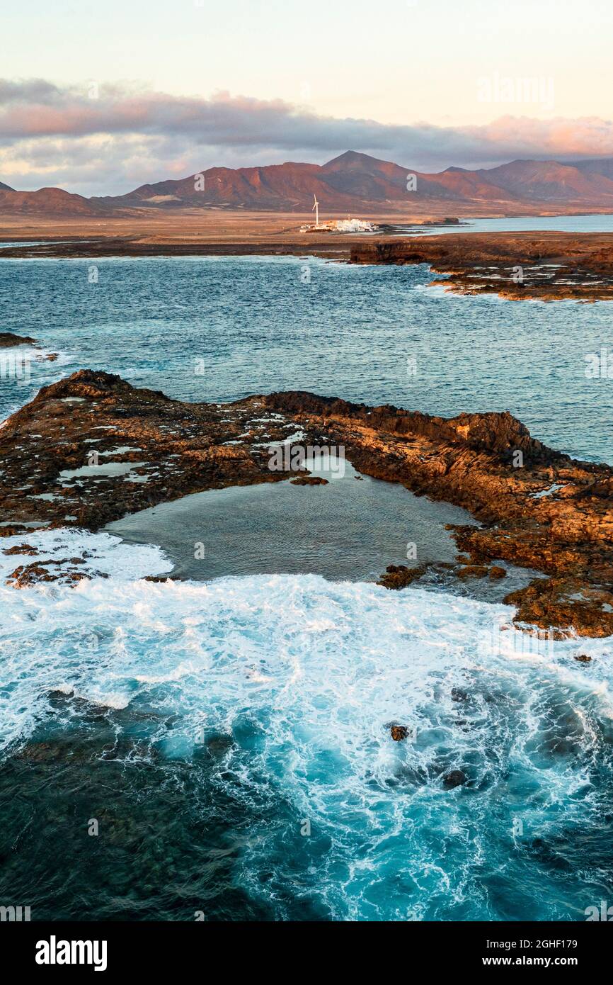 Vista aerea delle onde oceaniche che si infrangono sulle rocce al tramonto, Punta Jandia, Fuerteventura, Isole Canarie, Spagna Foto Stock