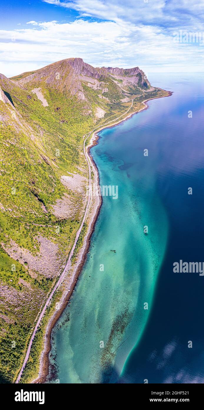 Vista aerea della strada costiera vicino al mare cristallino ai piedi del monte Husfjellet, Steinfjord, Senja, contea di Troms, Norvegia Foto Stock