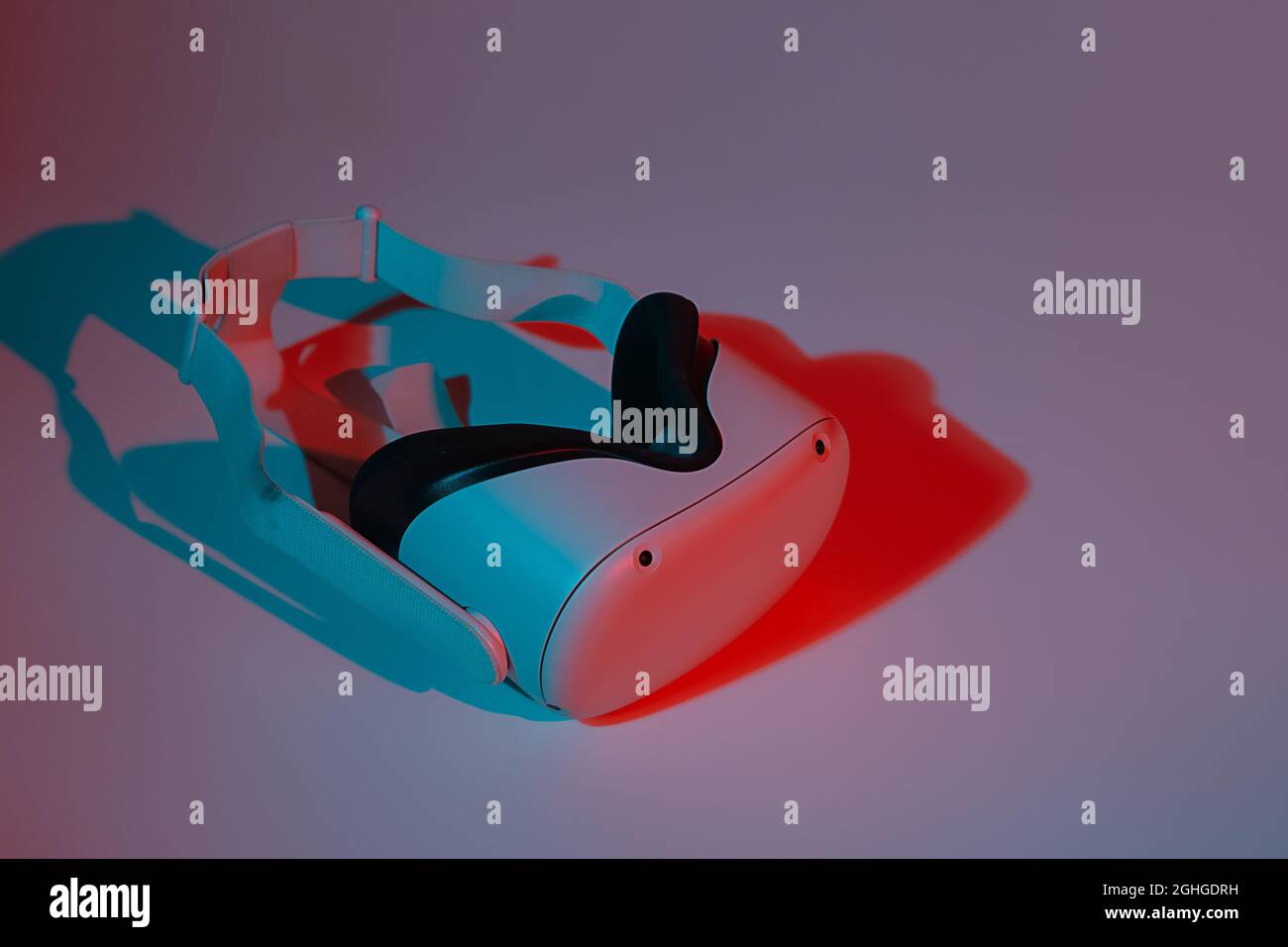 Casco per realtà virtuale su sfondo bianco con luce al neon. Realtà virtuale, futuro, gadget, concetto di tecnologia. Foto Stock