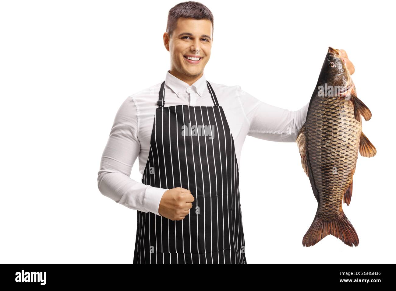 Giovane chef maschile che tiene un grosso pesce carpa e sorridente isolato su sfondo bianco Foto Stock