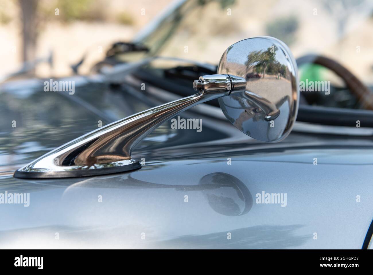 Lo specchio retrovisore cromato lucido di un'auto sportiva senza tempo ha linee lunghe e curvilinee. Foto Stock