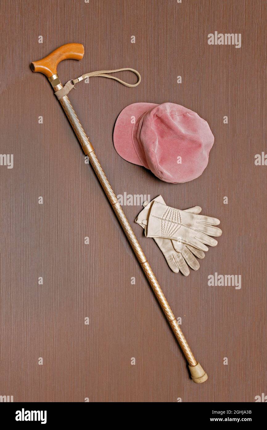 Bastone da passeggio in metallo color oro con cappello e guanti in pelle Foto Stock
