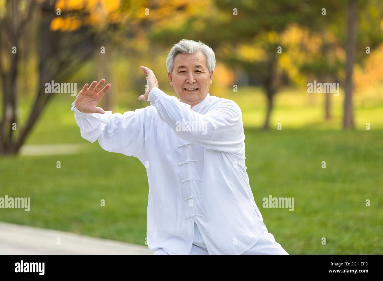 Uomo anziano allegro che pratica Tai Chi nel parco Foto Stock