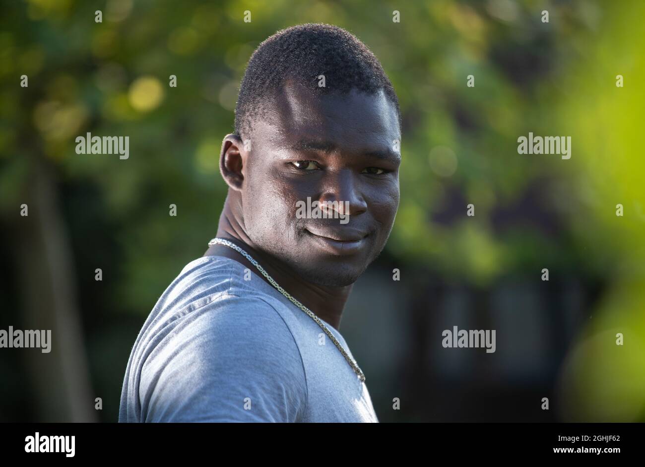 Ritratto di sorridente e soddisfatto giovane africano in piedi nel parco Foto Stock