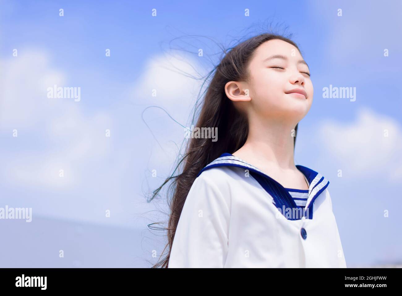ragazza studentesca rilassata godendo brezza estiva, sorridente con gli occhi chiusi Foto Stock