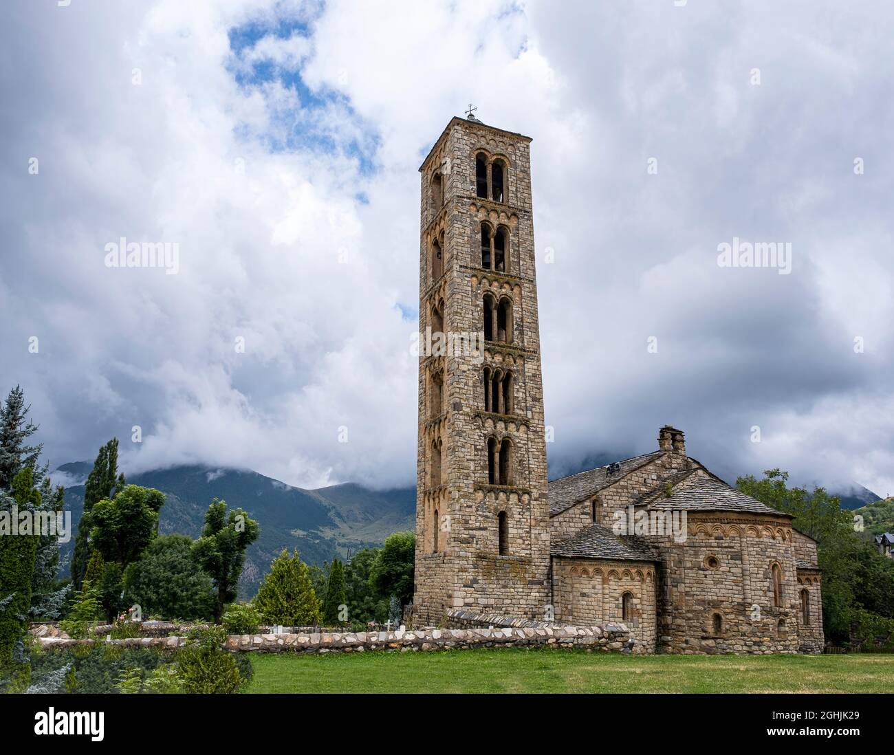 Chiesa romanica di San Clemente di Tahull, con il suo alto campanile e le montagne dei Pirenei Lleida sullo sfondo in una giornata nuvolosa, hori Foto Stock
