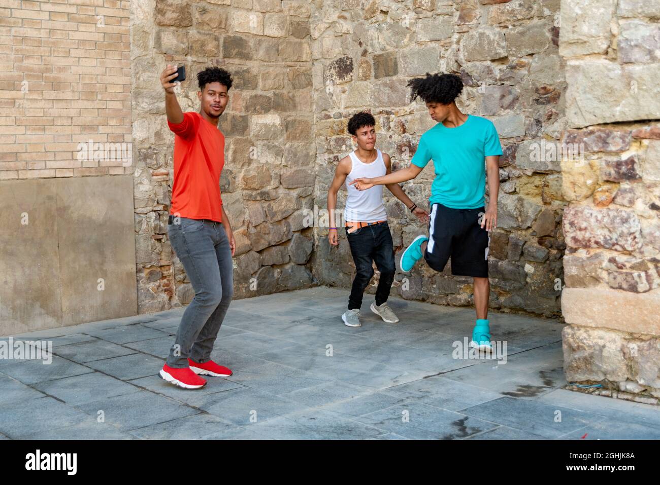 Tre amici latini maschi che ballano per strada e la registrano Foto Stock