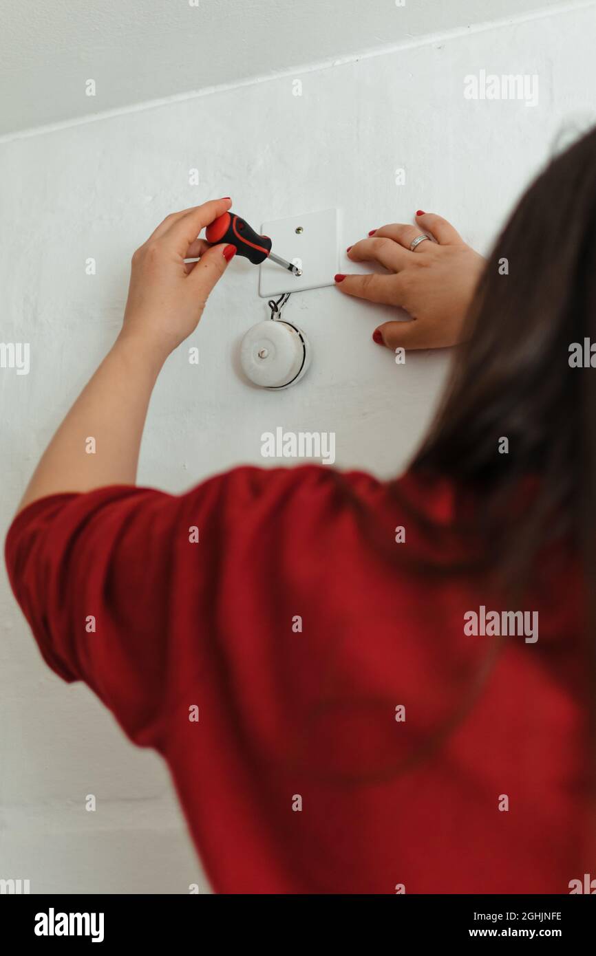 Primo piano di una donna con unghie dipinte riparando un campanello con un cacciavite Foto Stock