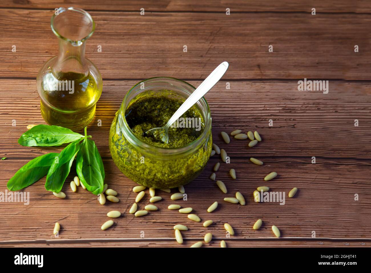 Preparazione del pesto genovese, la salsa pronta nel vaso di vetro, pinoli, olio d'oliva e foglie di basilico Foto Stock