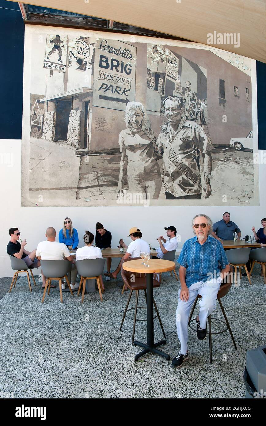 Giovani patroni che si godono un drink sul patio del Brig di Brandelli sotto un murale classico dipinto da Art Mortimer su Abate Kinney Blvd. A Venezia, CA Foto Stock