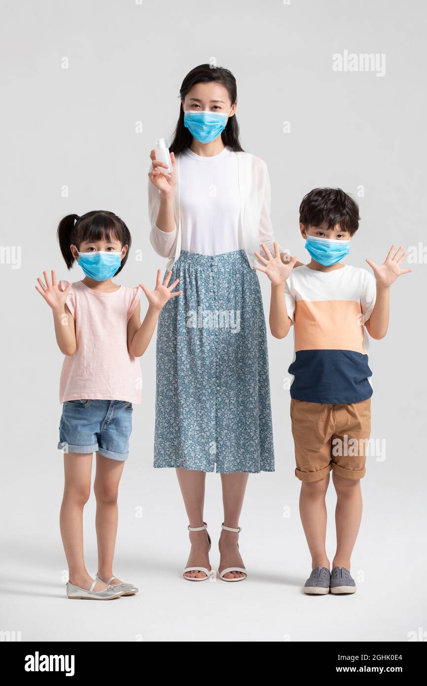 Bambini che usano l'igienizzatore per le mani con l'aiuto della madre Foto Stock