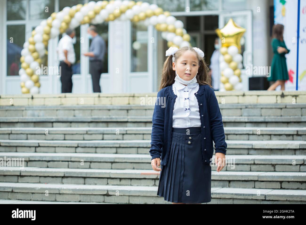 Bella ragazza in maschera andando a 1 grado a scuola Foto Stock