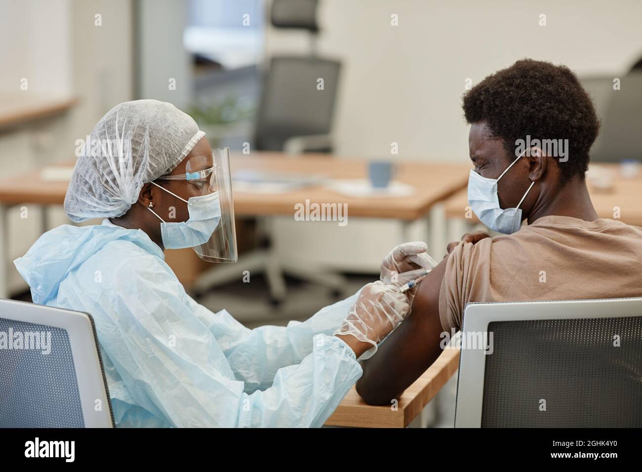Spaventato il giovane uomo nero che chiude gli occhi quando ottiene il colpo di vaccino contro il coronavirus Foto Stock