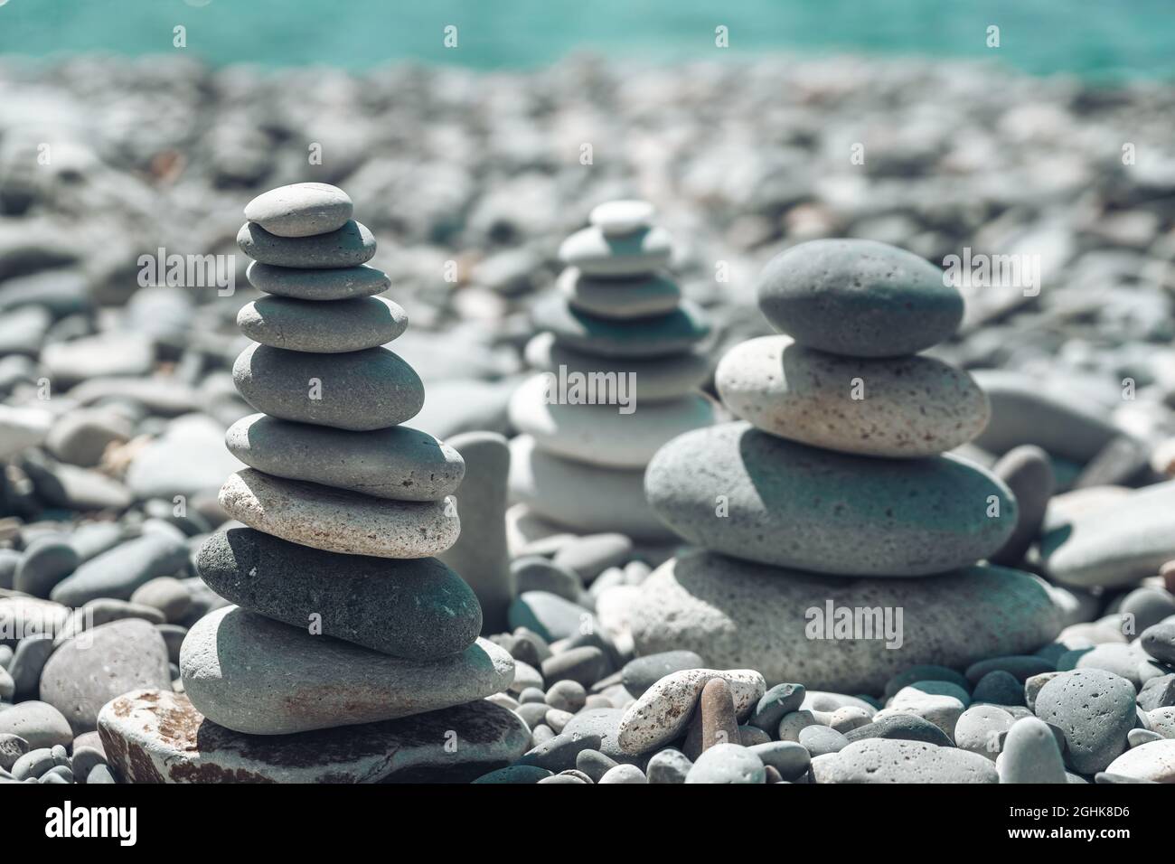 Equilibrata piramide di ciottoli sulla spiaggia in una giornata di sole. Abstract Sea bokeh sullo sfondo. Messa a fuoco selettiva. Pietre Zen sulla spiaggia di mare, meditazione Foto Stock