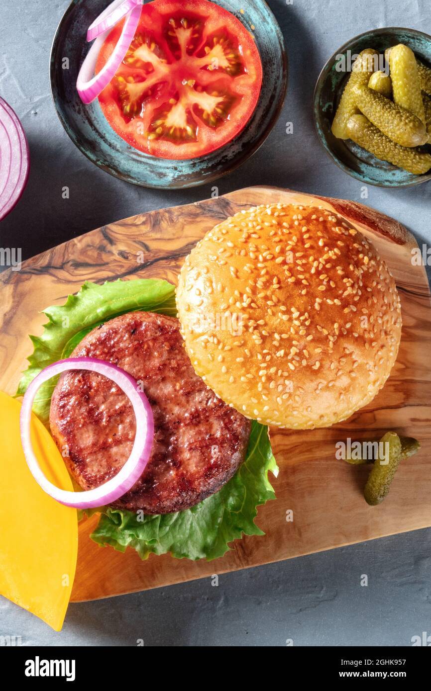 Ricetta di hamburger. Ingredienti classici per hamburger di carne con polpette di manzo, panini al sesamo, pomodoro, cipolla, foglia di insalata e sottaceti, sparati dall'alto Foto Stock