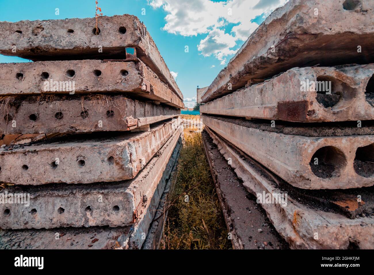 Lastre di calcestruzzo usate si posano sopra l'una dell'altra vicino ad un'area industriale. Foto Stock