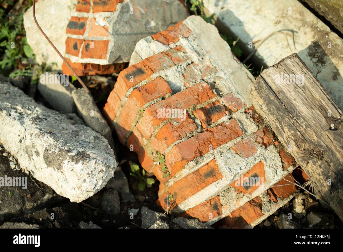 Pezzi rotti del muro. Una casa in rovina. Parti fatte di mattone. Scarico rifiuti edili. Il mattone rosso è rotto e si trova sulla strada. Foto Stock