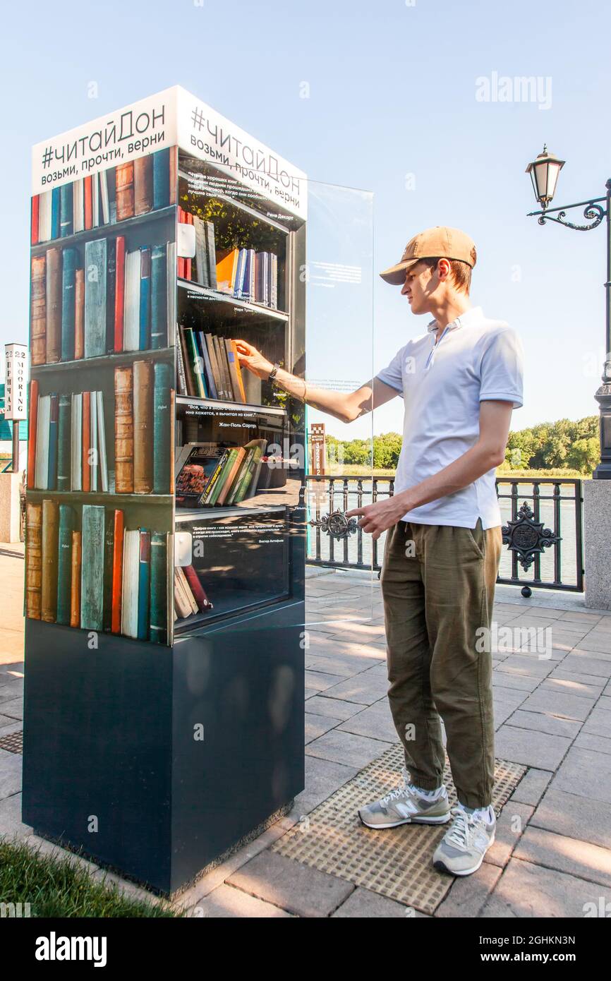 Il giovane uomo prende i libri da un punto di scambio libero del libro sull'argine. Rostov-on-Don, Russia, agosto 07 2021. Foto Stock