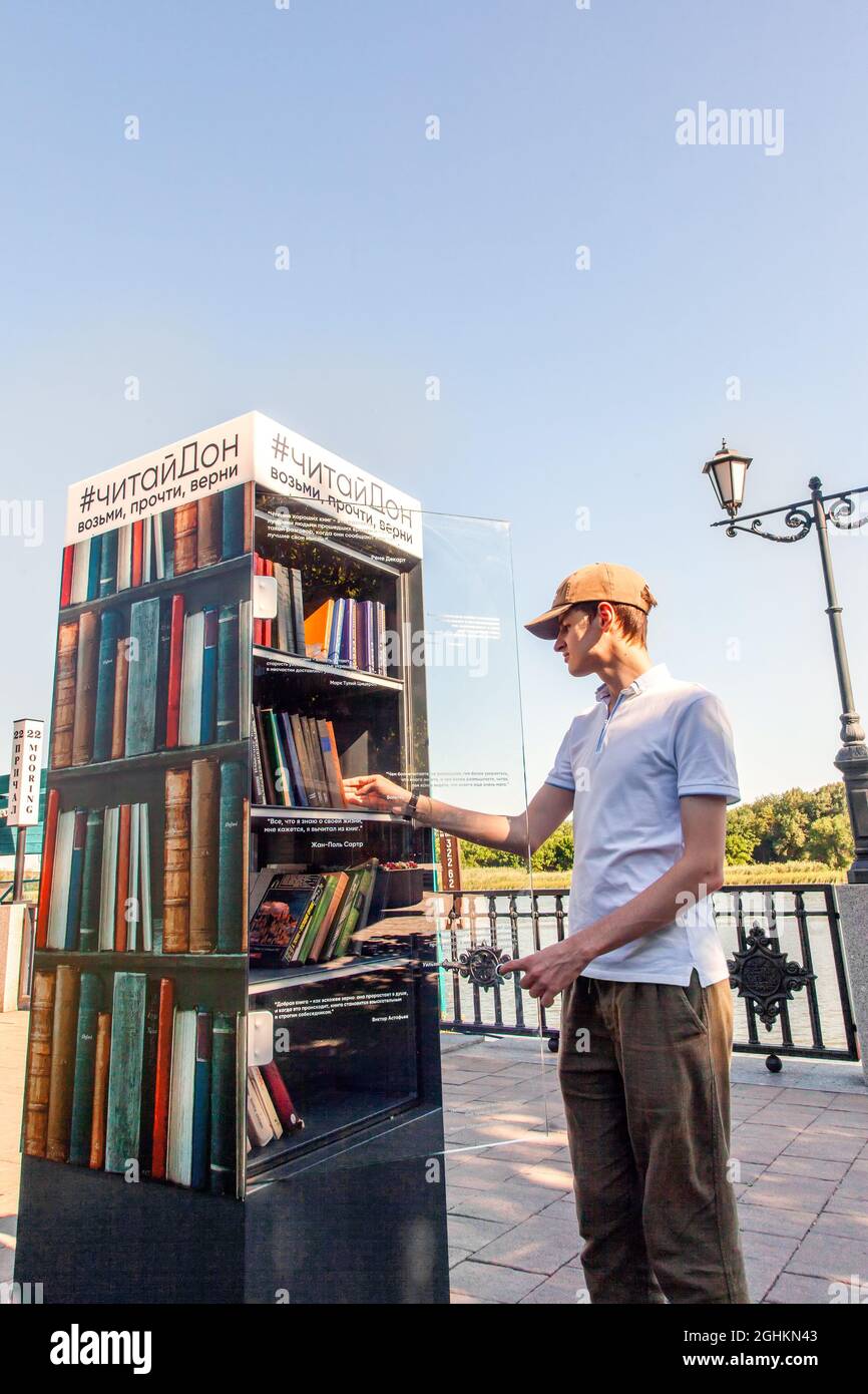 Il giovane uomo prende i libri da un punto di scambio libero del libro sull'argine. Rostov-on-Don, Russia, agosto 07 2021. Foto Stock