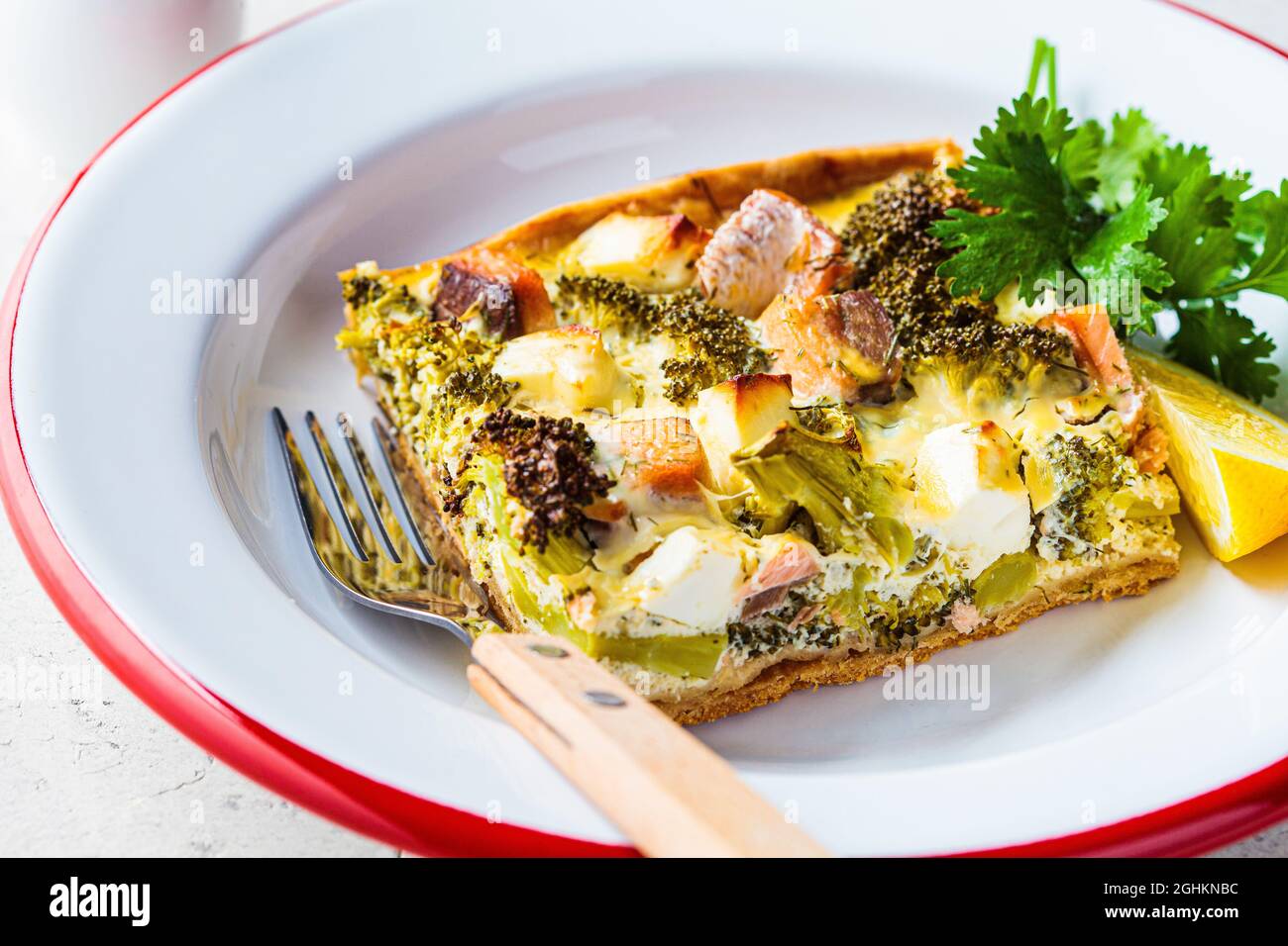 Pezzo di quiche torta con salmone e broccoli in piatto, primo piano. Foto Stock