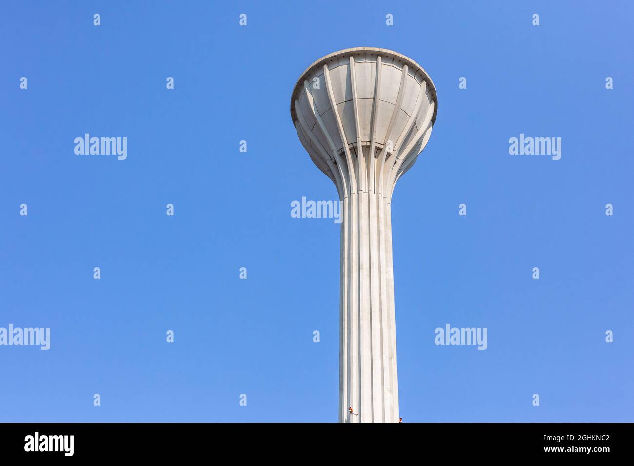 Alta torre dell'acqua struttura del serbatoio di calcestruzzo contro cielo blu che contiene migliaia litri o galloni di acqua per consumo locale di bere. Foto Stock