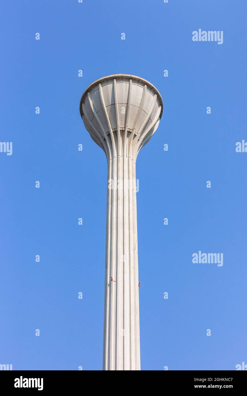 Alta torre dell'acqua struttura del serbatoio di calcestruzzo contro cielo blu che contiene migliaia litri o galloni di acqua per consumo locale di bere. Foto Stock