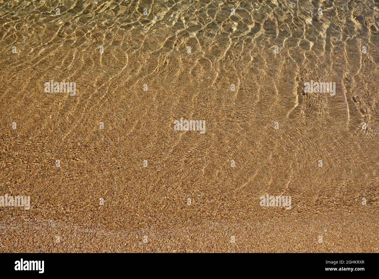Primo piano delle acque cristalline e sabbiose della spiaggia di Manganari a iOS Grecia Foto Stock