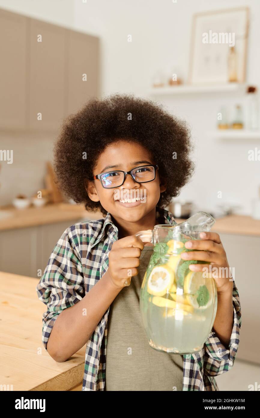 Sorridente ragazzino di etnia africana che tiene brocca con limonata fresca e fresca fatta in casa Foto Stock