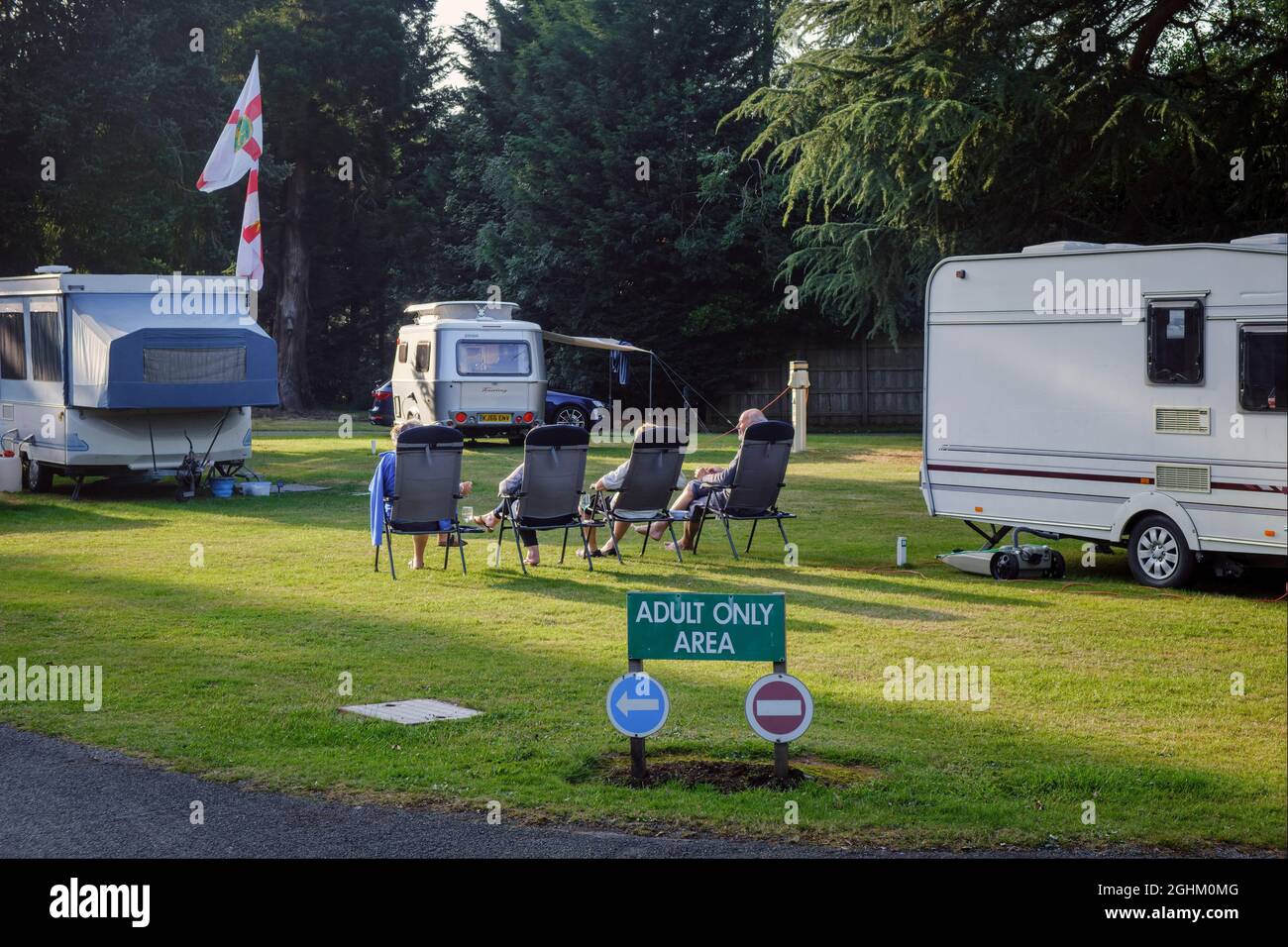 Caravanners rilassarsi al sole serale sulla sezione adulti solo su un campeggio, Stanmore Hall Touring Park, Bridgnord, Shropshire Foto Stock