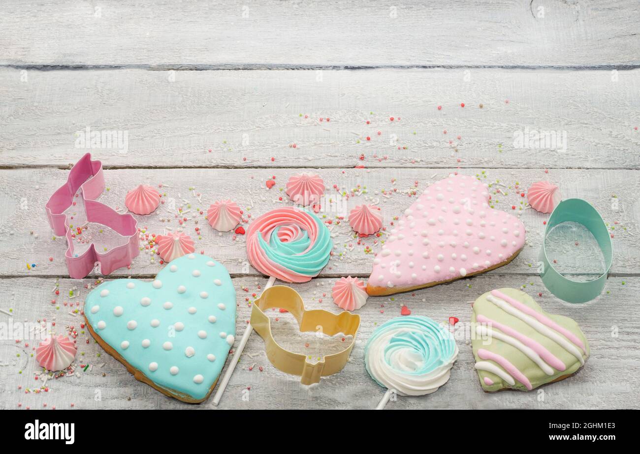 Cottura di Pasqua cottura di fondo con biscotti di pasqua color pastello e meringa., taglierine biscotti., spolverini di zucchero. Sfondo rustico in legno, pianeggiante Foto Stock