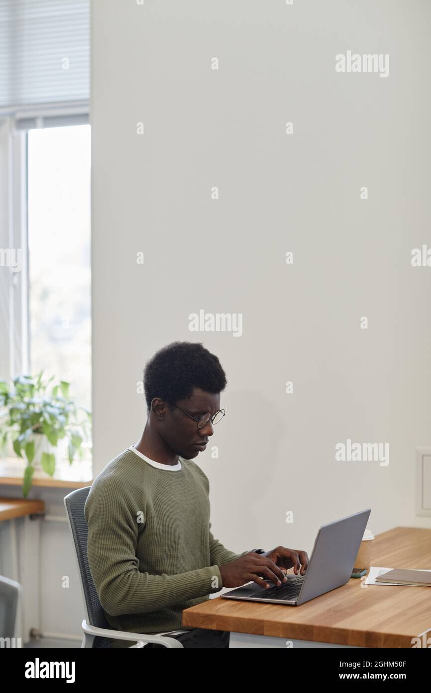 Accigliarsi serio giovane uomo d'affari che lavora sul laptop alla scrivania d'ufficio e rispondere alle e-mail del cliente o del socio d'affari Foto Stock