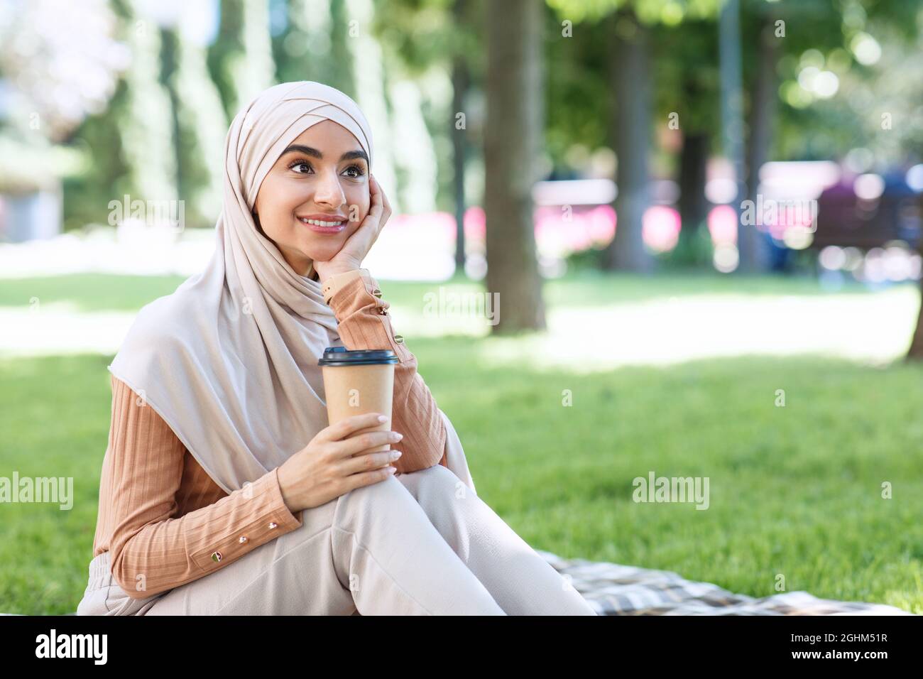 Sorridente ragazza musulmana araba in hijab prendere una pausa dal lavoro o dallo studio, rilassarsi nel parco Foto Stock